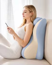 Woman using a smartphone while sitting on a cushion with blue and beige colors.