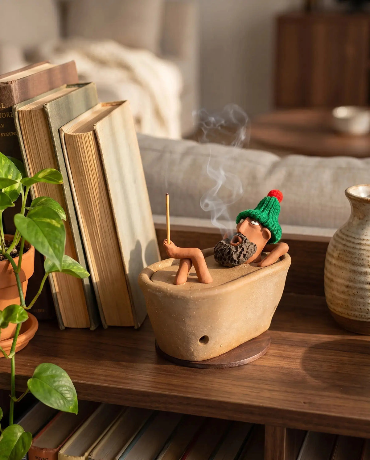 Lazy Bath Man incense burner on a living room bookshelf