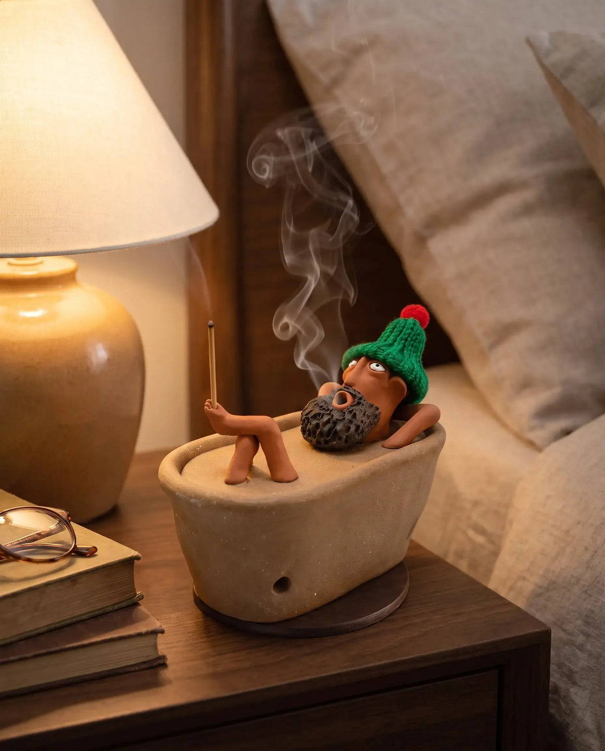 Lazy Bath Man incense burner on a bedroom nightstand at night