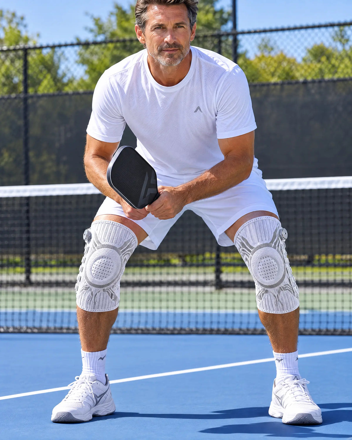 White knee sleeves on both knees playing pickleball